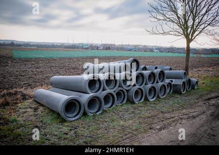 su una strada ci sono tubi di calcestruzzo che devono essere posati Foto Stock