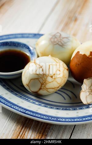 Primo piano Cinese cibo bollito marmo Erbal Tea uovo su rustico tavolo in legno. Cha Ye Dan con salsa di soia Foto Stock