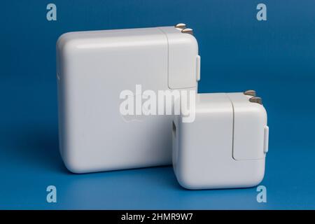 Manila, Filippine - 12 febbraio 2022: Apple MacBook Pro e iPad Air Charger isolato in sfondo blu Foto Stock