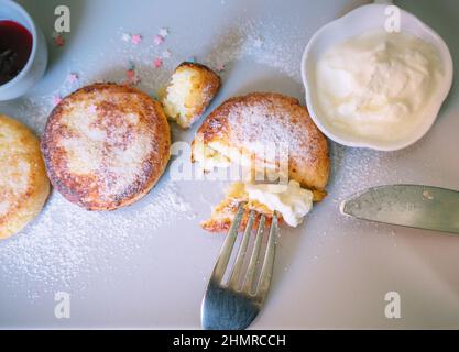 mangiare frittelle di formaggio fresco con panna acida e marmellata di frutti di bosco Foto Stock