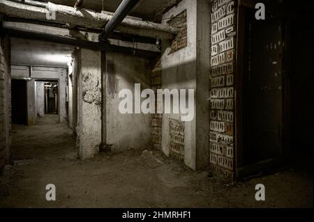 Seminterrato abbandonato con elettricità e fogne nel seminterrato di un edificio di nove piani dell'epoca sovietica senza porte Foto Stock