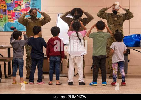 1 febbraio 2022 - Joint base McGuire-Dix-Lakehurst, New Jersey, USA - US Air Force Airmen, assegnato alla Task Force-Liberty, cantando la canzone 'testa, spalle, ginocchia e piedi'' con i bambini afghani nel Liberty Village sulla Joint base McGuire-Dix-Lakehurst, New Jersey, 1 febbraio 2022. Il Dipartimento della Difesa, attraverso il comando del Nord degli Stati Uniti, e a sostegno del Dipartimento della sicurezza interna, sta fornendo trasporto, alloggio temporaneo, screening medico, e supporto generale per almeno 11.000 sfollati afghani a Liberty Village, in strutture permanenti o temporanee, il più rapidamente possibile. T Foto Stock