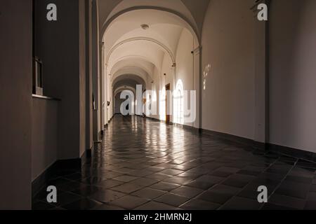 Splendida vista interna di un lungo corridoio con forma ad arco e pavimento piastrellato in ceramica Foto Stock