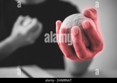 L'uomo massaggia il dito con palle da tennis. Concetto di sindrome da ufficio. L'area del sintomo dolore è visualizzata in rosso. Primo piano estremo. Nero e bianco Foto Stock