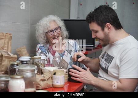 Madre anziana e figlio adulto che prepara alcuni dolci mentre parla felicemente. Foto Stock