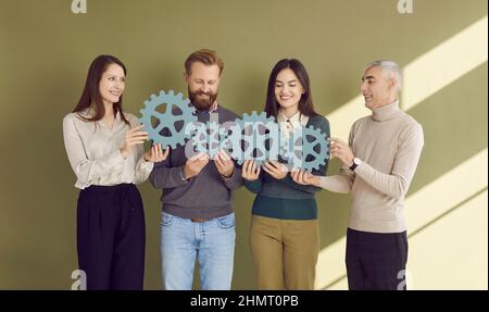 Persone che tengono e collegano gli ingranaggi in legno che simboleggiano lo sviluppo, il lavoro di squadra e il successo. Foto Stock