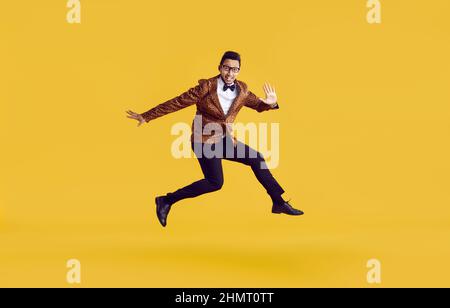 Felice ragazzo divertente giovane in giacca leopardo saltando in aria isolato su sfondo giallo Foto Stock