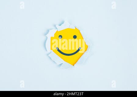 Sorridendo faccia felice sotto una carta strappata, emozioni positive, buon feedback dei clienti, ridendo Foto Stock