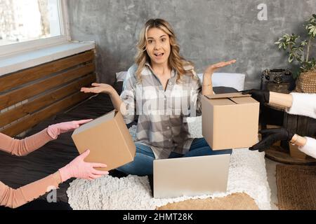 Ritratto di giovane donna bionda bionda che lavora seduto sul tappeto con molte scatole di cartone dal servizio di consegna Foto Stock