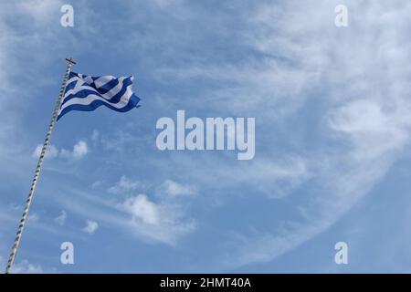 La bandiera greca sventola nel vento contro un bel cielo blu Foto Stock