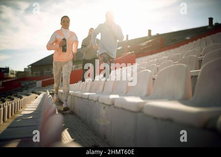 Un gruppo di giovani corre in tribuna durante un allenamento in una bella giornata allo stadio. Sport, atletica, atleti Foto Stock