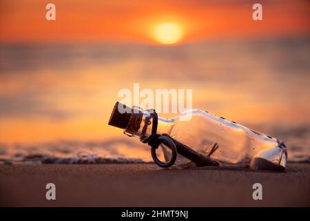 Messaggio in bottiglia contro il sole che tramonta verso il basso Foto Stock