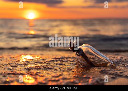 Messaggio in bottiglia contro il sole che tramonta verso il basso Foto Stock