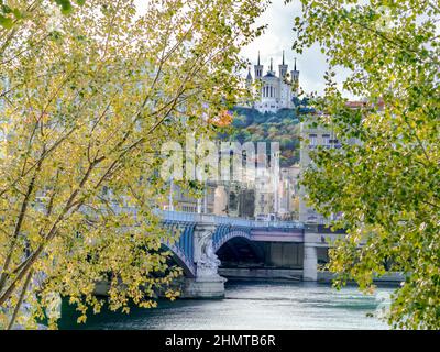 Basilica di Notre dame de fourvière, ponte Lafayette, il fiume Rodano e il parco degli hauteurs. Vista da Quai du Général Sarrail tra foglie di albero. Foto Stock