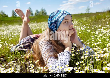 Bella donna sdraiata su campo margherita. Ragazza che riposa nel parco primaverile. Godetevi la vita, divertendosi, svago, relax, primavera, concetto di stile di vita Foto Stock