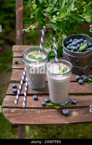Cocktail sano aromatizzato con mirtilli e latte. Frullato dolce con frutti di bosco e yogurt. Foto Stock
