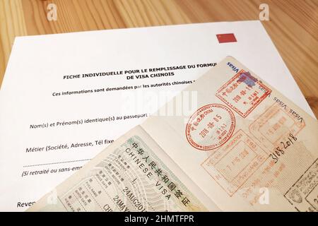 Ha aperto il passaporto francese sulla parte superiore di un modulo di richiesta per un visto turistico cinese. Foto Stock