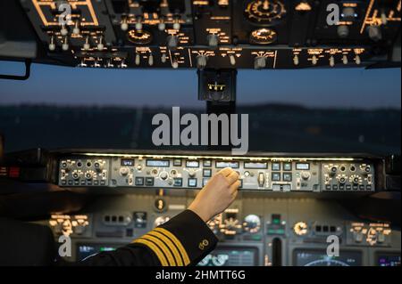 Primo piano della mano di un pilota sul pannello di controllo di un aeroplano. Foto Stock
