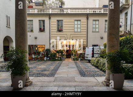 Un negozio di fiori con molte piante in vaso esposto sul fronte nel cortile di un antico palazzo nel centro storico di Torino, Piemonte, Italia Foto Stock