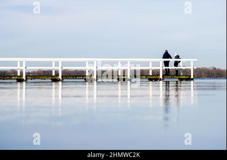 Bad Zwischenahn, Germania. 12th Feb 2022. Una coppia si erge su un molo al Zwischenahner Meer in condizioni di sole. Credit: Hauke-Christian Dittrich/dpa/Alamy Live News Foto Stock