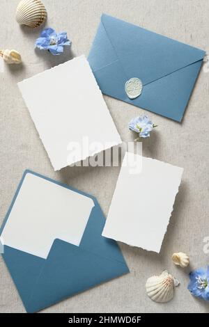 Nautica salvare le carte data mockups, buste blu, seashell su sfondo beige. Modelli di biglietto d'invito per matrimoni. Disposizione piatta, vista dall'alto, spazio di copia. Foto Stock