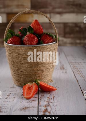 Il cesto di frutta è una soluzione ideale per gli interni. La foto è stata scattata contro un muro di mattoni e su un tavolo di legno. L'immagine è fatta con colori caldi Foto Stock