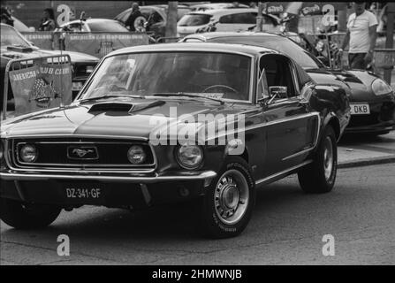 Foto in scala di grigi di una vecchia auto Ford Mustang classica in una strada Foto Stock