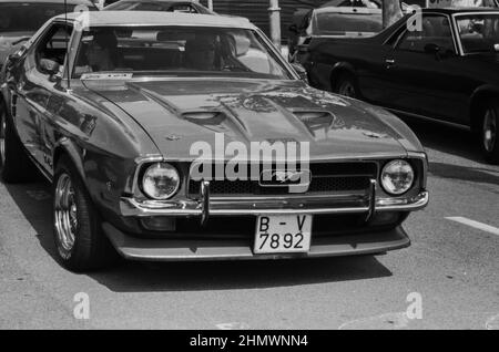 Foto in scala di grigi di una vecchia auto Ford Mustang classica in una strada Foto Stock