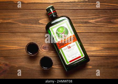 Ternopil, Ucraina - 24 maggio 2021: Una bottiglia di liquore Jagermeister e due bicchieri su sfondo di legno vista dall'alto Foto Stock