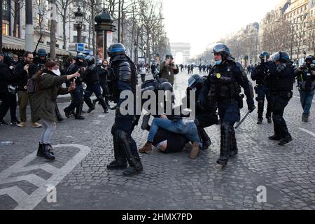 I poliziotti francesi anti-sommossa si scontrano con un protester sugli Champs Elysees a Parigi vicino all'Arco di Trionfo il 12 febbraio 2022, quando convogli di manifestanti così chiamati convoi de la Liberte arrivarono nella capitale francese. Migliaia di manifestanti in convogli, ispirati dagli autotrasportatori canadesi che paralizzavano il traffico di frontiera con gli Stati Uniti, si sono recati a Parigi da tutta la Francia il 11 febbraio, con alcuni che speravano di bloccare la capitale in opposizione alle restrizioni del Covid-19 nonostante gli avvertimenti della polizia di tornare indietro. I manifestanti includono molti attivisti anti-vaccinali, ma anche persone che protestano contro la rapida risina Foto Stock