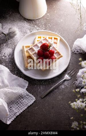 Cialde fatte in casa con fragole, lamponi e zucchero in polvere su piatto bianco. Vista dall'alto Foto Stock