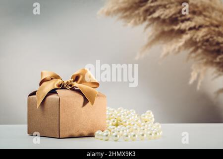 Confezione regalo in carta Kraft con arco in nastro dorato su bianco Foto Stock