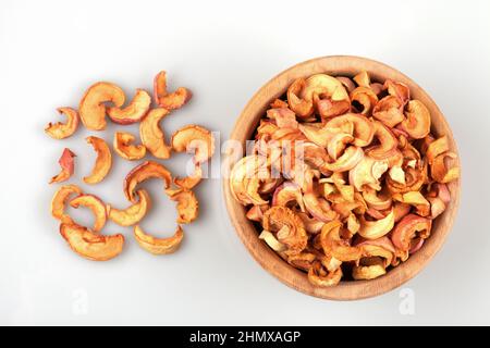 Ciotola di legno piena di fette di mela secca, fondo bianco Foto Stock
