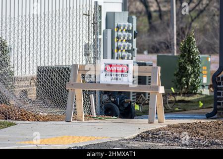 Scatto orizzontale di una barricata di costruzione di fronte ad un nuovo complesso di appartamenti in costruzione. Il segnale dice: Pericolo Area limitata. Foto Stock