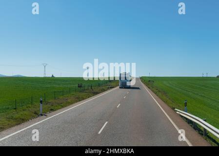 Carrello che guida lungo un rettilineo lungo tra i campi verdi in una giornata limpida. Foto Stock