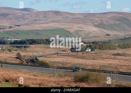 GB Railnight classe 66 locomotiva 66709 sulla linea principale della costa occidentale nella campagna della Cumbria passando Scout Green con un treno di negozi dell'esercito Foto Stock