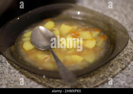 Ciotola di zuppa. Cucchiaio di zuppa. Pranzo a metà pasto. Cibo in cucina. Piatti a tavola. Foto Stock