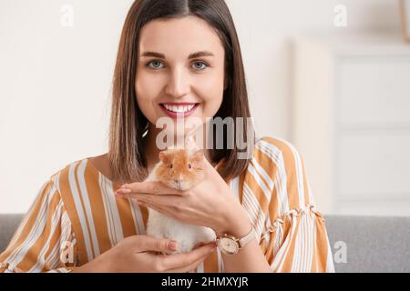 Bella giovane donna con cavia carina a casa Foto Stock