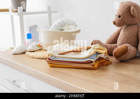 Accatastare i vestiti del bambino ed il picchiettio sul cassettiere di legno nella stanza dei bambini Foto Stock