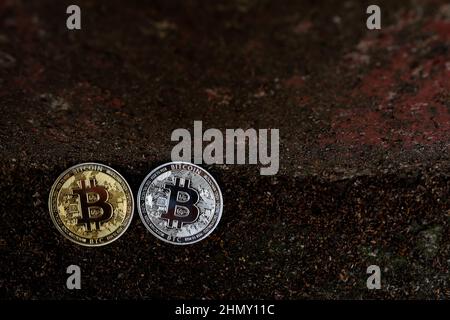 Bitcoin e cripto criptovaluta estrazione, crackdown e crash prezzo e concetto di FUD. Monete in Bitcoin cemento da parete scuro incrinato. Foto Stock