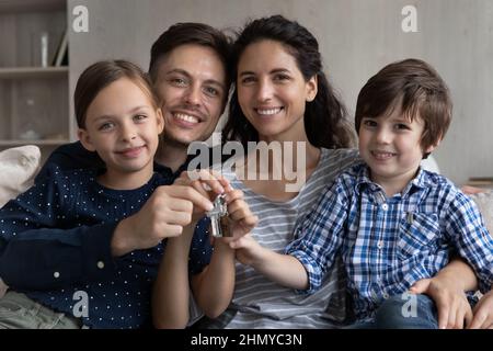 Coppia felice e due bambini che tengono le chiavi dalla nuova casa Foto Stock
