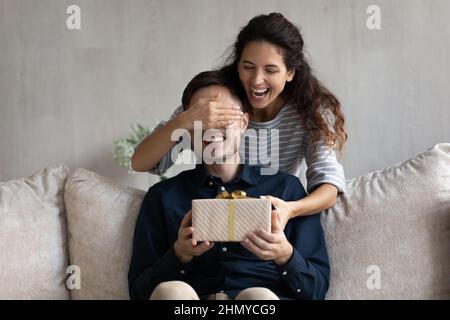 Giovane donna latina eccitata che dà il regalo di sorpresa al ragazzo eccitato Foto Stock