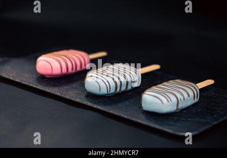 Dessert in forma di gelato alla pop-sicle ricoperto di cioccolato rosa e blu. Foto Stock