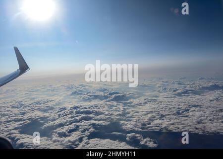 Voli economici, biglietti aerei biglietti aerei cielo blu brillante e nuvola fuori dalla finestra dell'aereo mentre volano alto sopra l'aria. Foto Stock