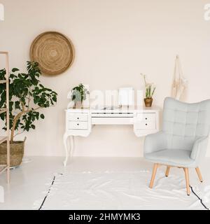 Elegante area di lavoro in casa. Interni scandinavi. Scrivania bianca e poltrona, grande casalinga Foto Stock