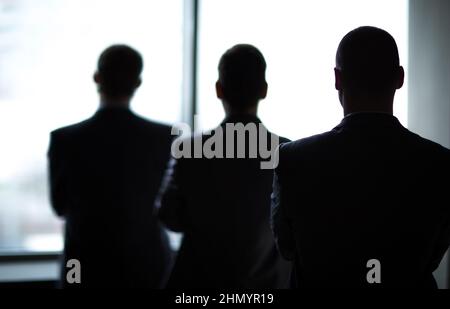 silhouette di tre uomini d'affari in ufficio Foto Stock
