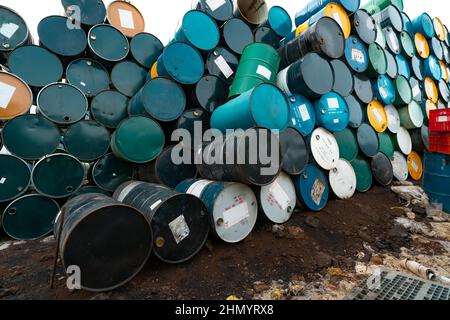 Vecchie botti chimiche. Barile per sostanze chimiche pericolose con etichetta di avvertenza. Tamburo dell'olio blu, verde, giallo e nero. Serbatoio dell'olio in acciaio. Magazzino rifiuti tossici. Pericolo Foto Stock