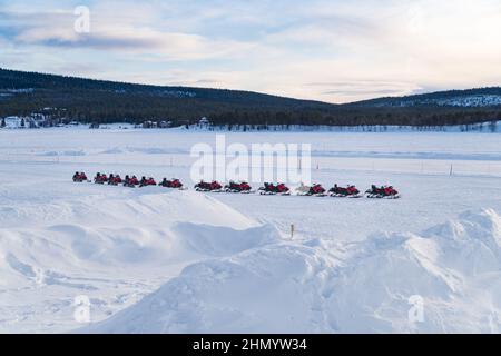 fila di motoslitte su un fiume ghiacciato in attesa di turisti Foto Stock