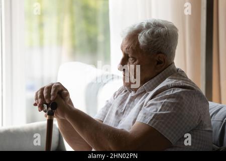 Triste depresso più vecchio 80s uomo che tiene la manopola del bastone gimp Foto Stock