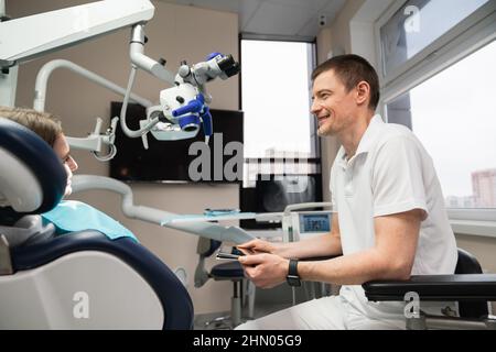 Il dentista comunica con il paziente negli studi dentistici utilizzando un tablet digitale Foto Stock